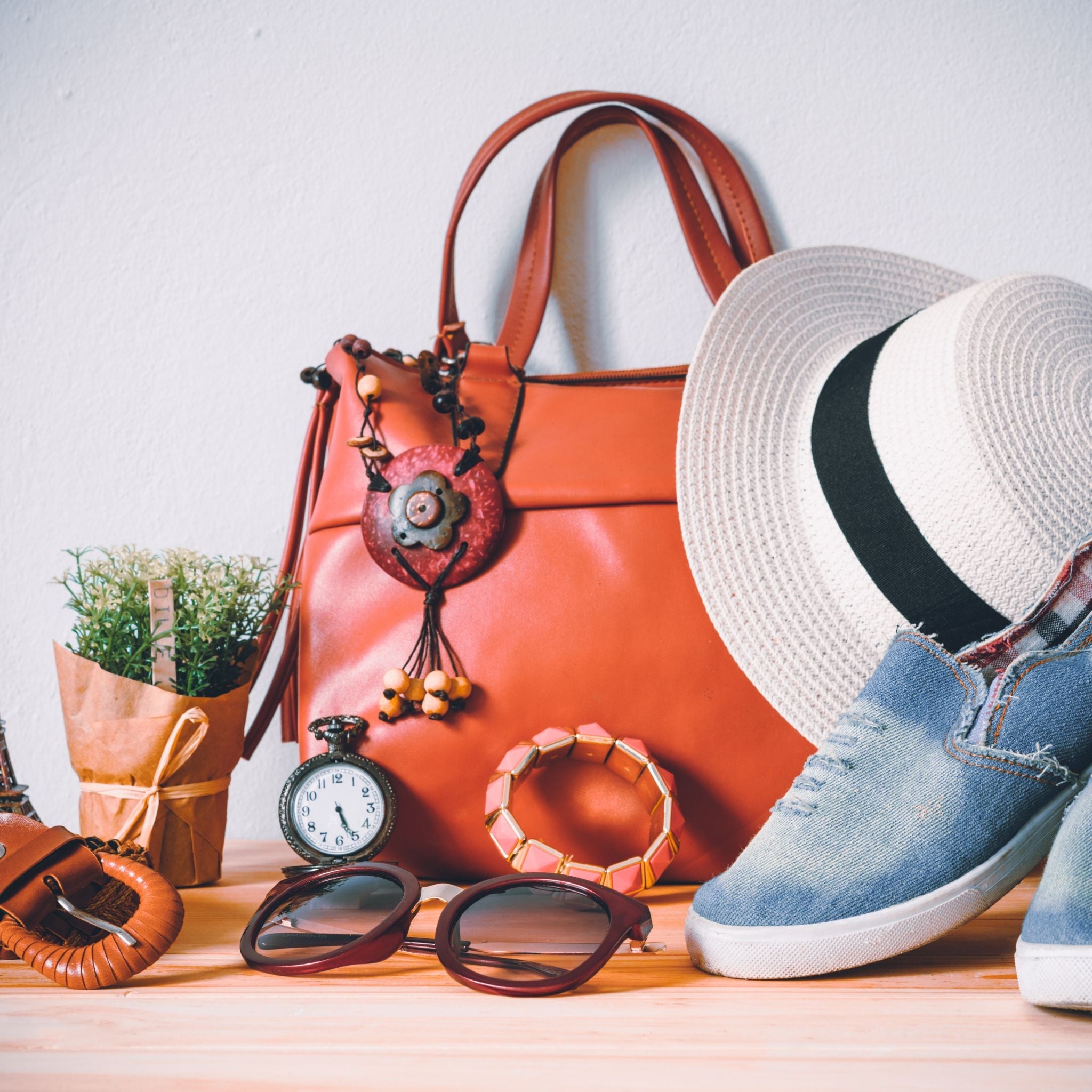 a photo of western accessories such as jeans sneakers, fedora hat, leather bag, glasses, bracelet and belt. 