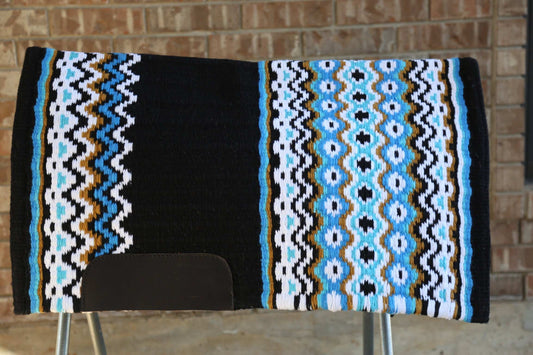 Custom Western Saddle Pad in Blue, Gold, White, Black geometric colors pattern on top of a saddle rack with brick wall background | Limited Edition