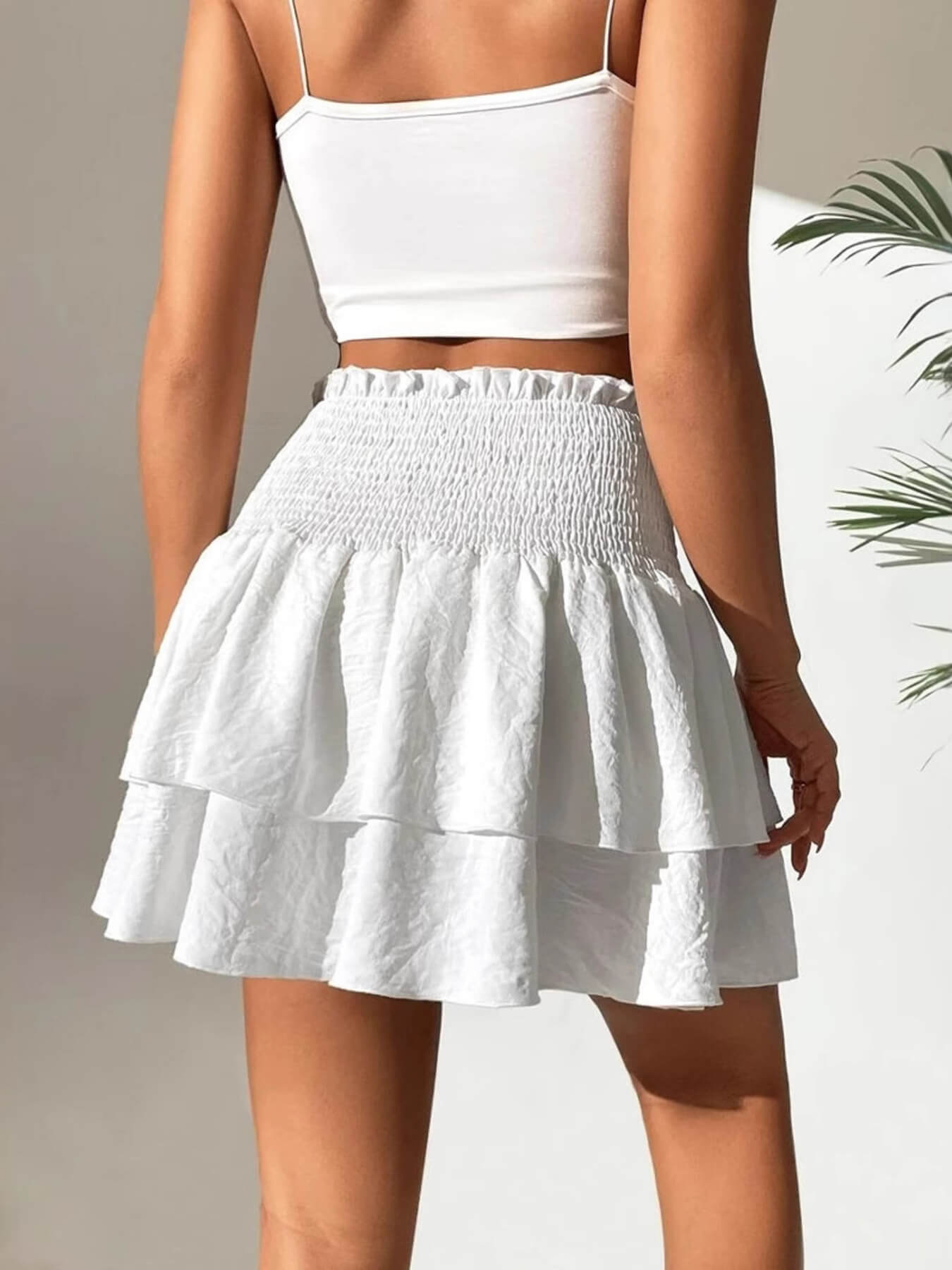 White tiered skirt worn by a woman on a neutral background