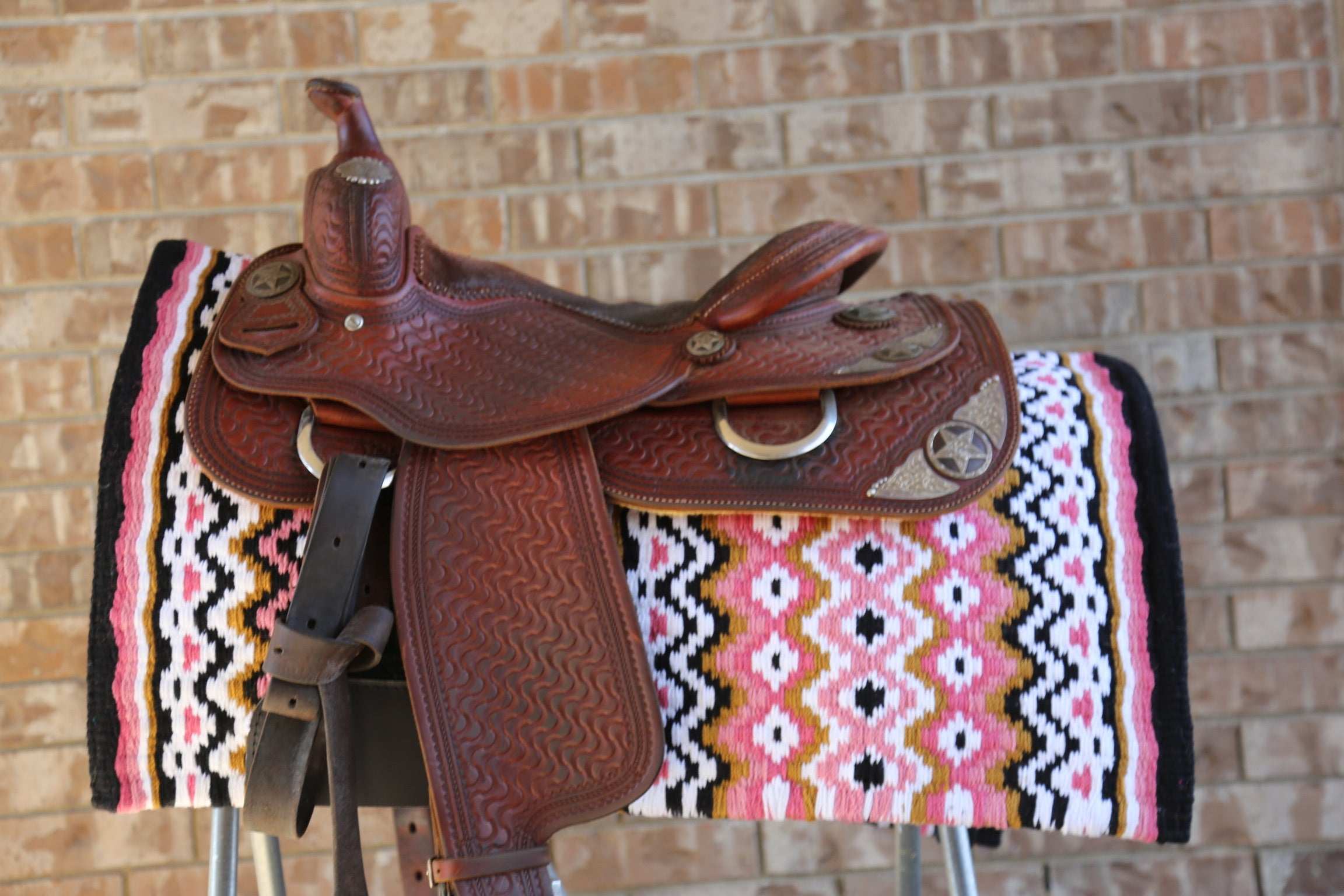 Custom Western Saddle Pad – Earth Tone Hues and Black Details | Limited Edition displayed on a saddle rack with western saddle on top