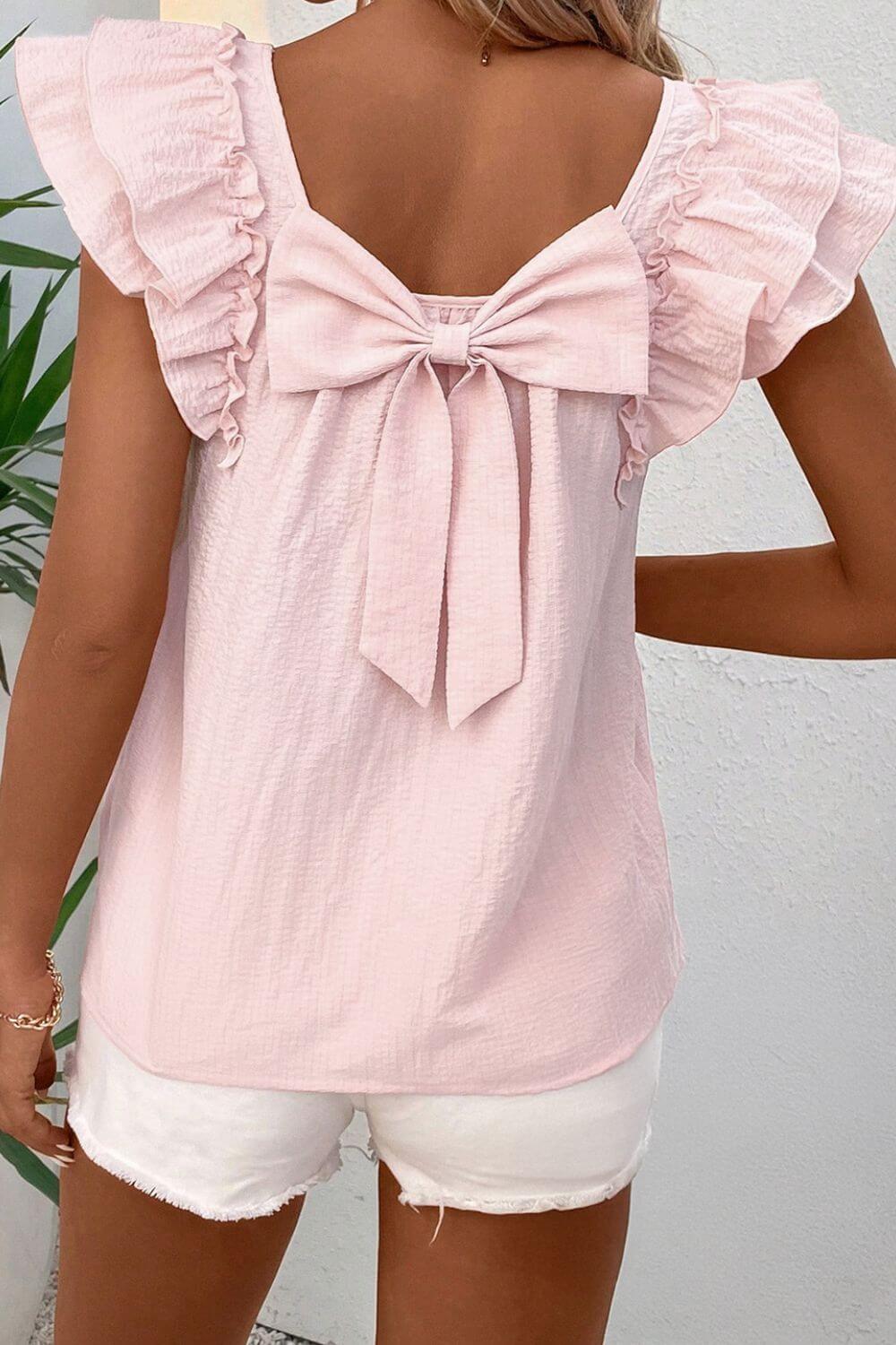 Pink blouse with ruffled sleeves and a bow at the back worn by a woman