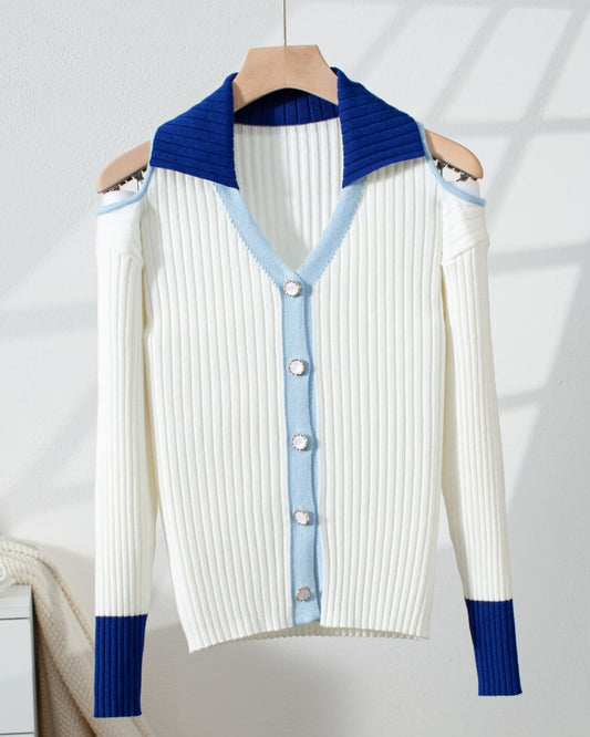 White cold shoulder cardigan sweater with blue and light blue accents on a hanger against a white background