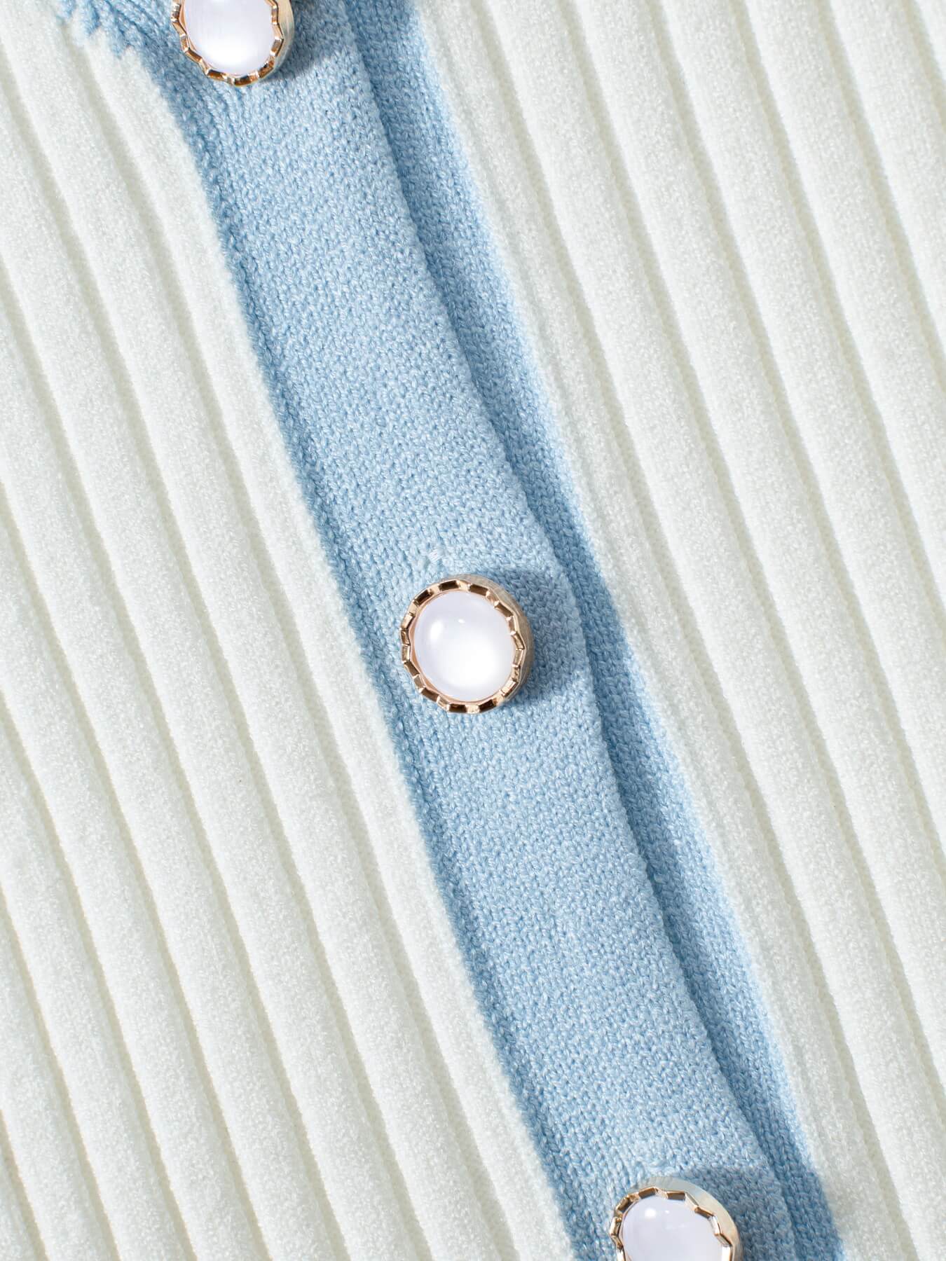 Close-up of a ribbed fabric with blue and white stripes and button details.