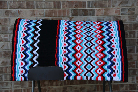 Colorful patterned saddle blanket on a chair against a brick wall.