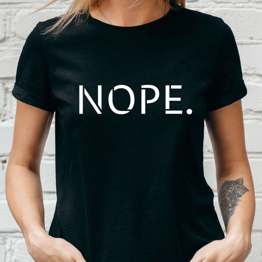 Person wearing a black t-shirt with 'NOPE.' text against a white brick wall.